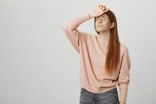 Mulher ruiva fofa e tímida posa como a rainha do drama, segurando a mão na testa e suspirando