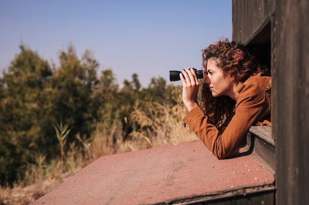 Foto grátis mulher ruiva lateral, olhando através de binóculos