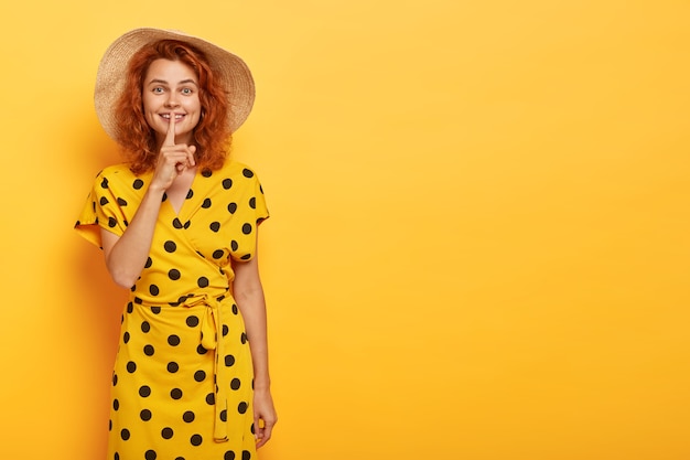 Foto grátis mulher ruiva linda posando com vestido polca amarelo e chapéu de palha