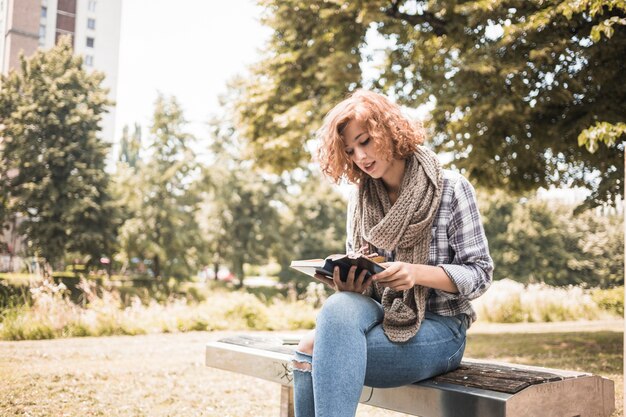 Mulher ruiva no livro de leitura de cachecol