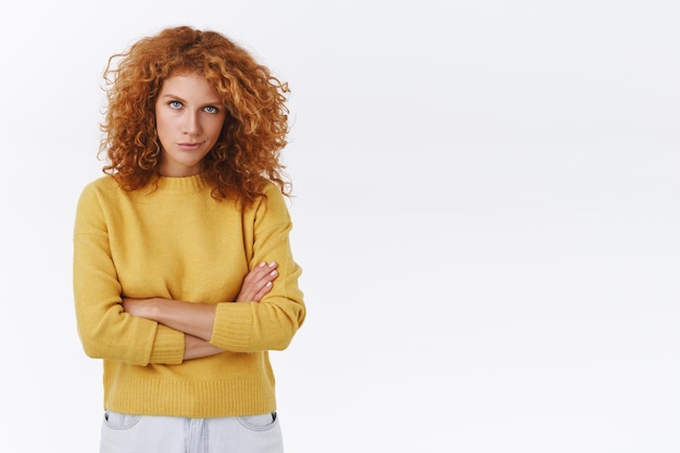 mulher ruiva tem um plano malicioso e maligno, sorri e olha por baixo da testa com os braços cruzados sobre o peito