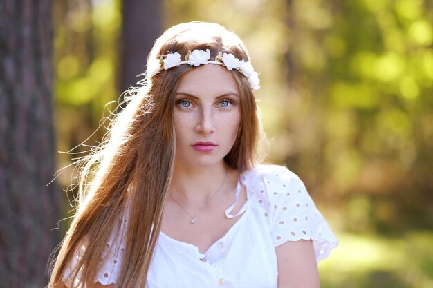 Mulher sardenta com aro de flor em seu retrato de cabeça na floresta de outono em uma luz do dia.