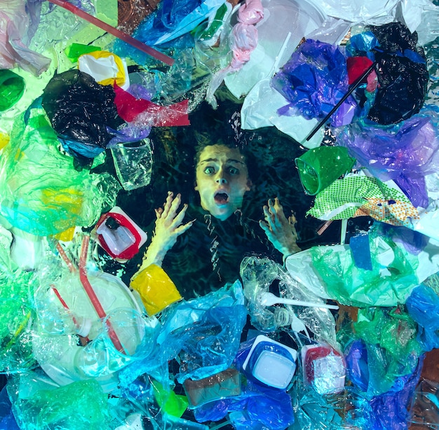 Foto grátis mulher se afogando na água sob a pilha de recipientes de plástico, lixo. garrafas e embalagens usadas enchendo o oceano mundial, matando pessoas.