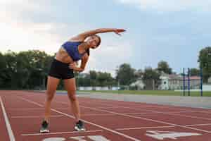 Foto grátis mulher se alongando na pista de corrida tiro completo