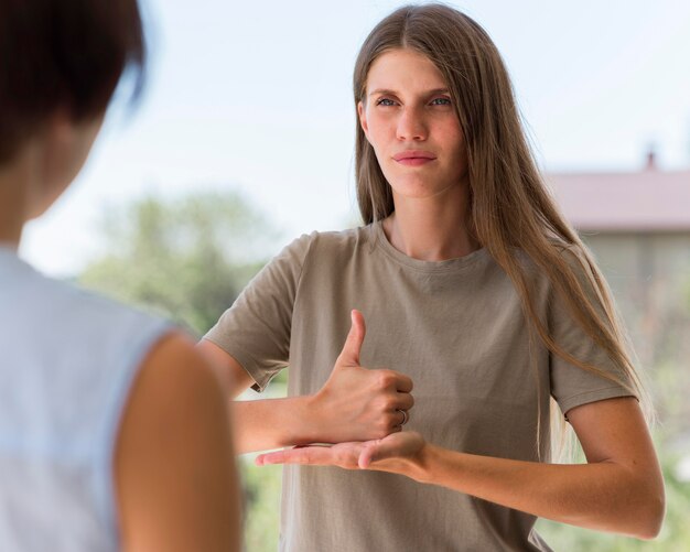 Mulher se comunicando por meio de linguagem de sinais ao ar livre