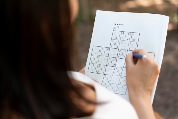 Mulher se divertindo sozinha com um jogo de sudoku no papel