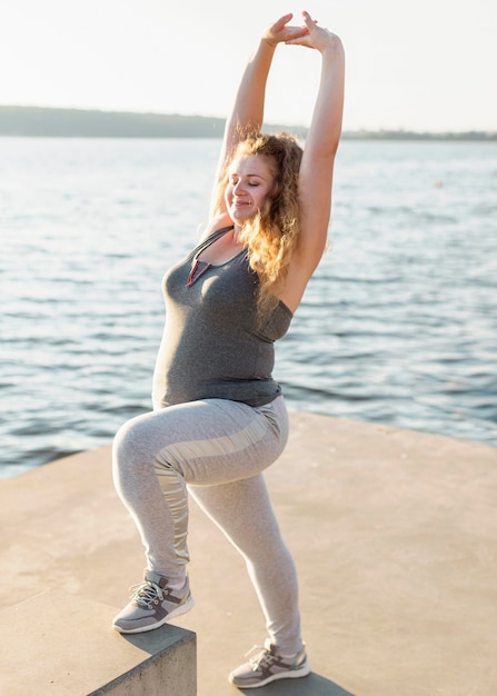 Foto grátis mulher se exercitando e se alongando à beira do lago