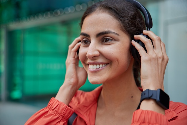 mulher se motiva para a prática de esportes se prepara para exercícios ao ar livre coloca fones de ouvido e usa pulseira para acompanhar os resultados retorna ao estilo de vida esportivo após a doença, pronta para a prática matinal