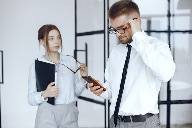 Mulher segura uma pasta. Parceiros de negócios em uma reunião de negócios. O homem usa o telefone. Pessoas com óculos