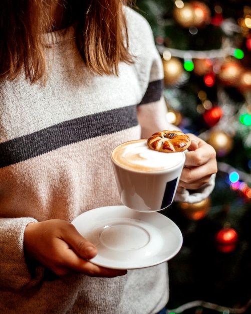Foto grátis mulher segura uma xícara de cappuccino com biscoito nele
