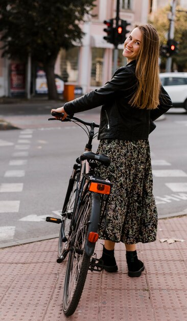 Mulher segurando a bicicleta por trás da foto