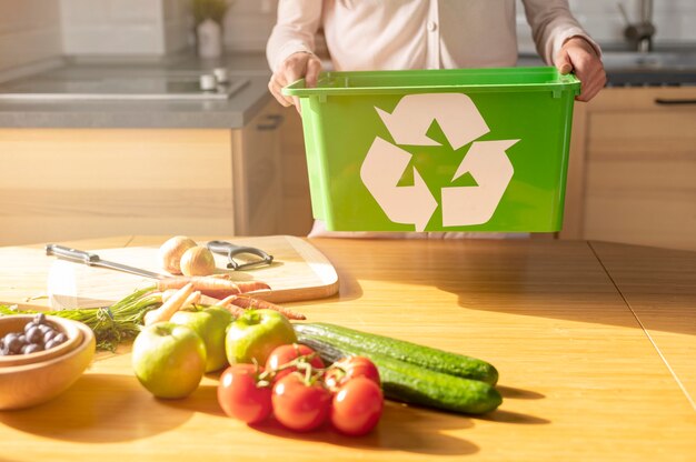 Mulher segurando a cesta de reciclagem na cozinha