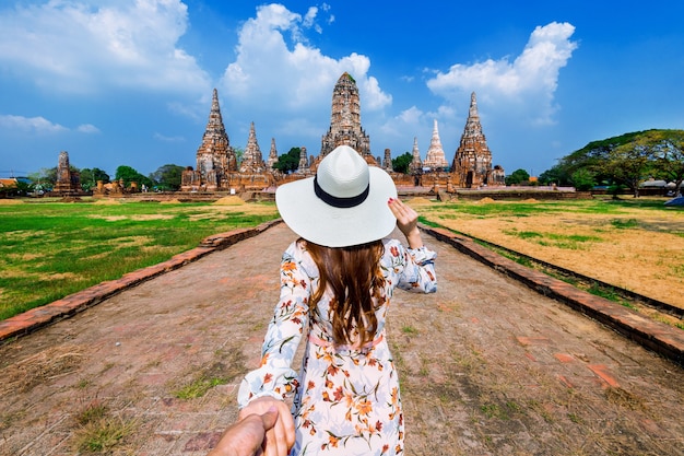 Mulher segurando a mão do homem e levando-o ao parque histórico de ayutthaya, templo budista wat chaiwatthanaram na tailândia.