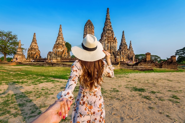 Mulher segurando a mão do homem e levando-o ao Parque Histórico de Ayutthaya, templo budista Wat Chaiwatthanaram na Tailândia.