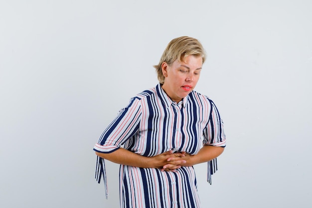 Mulher segurando as mãos entrelaçadas na barriga no fundo branco