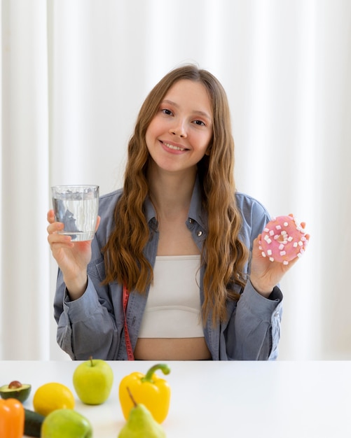 Foto grátis mulher segurando donut e água