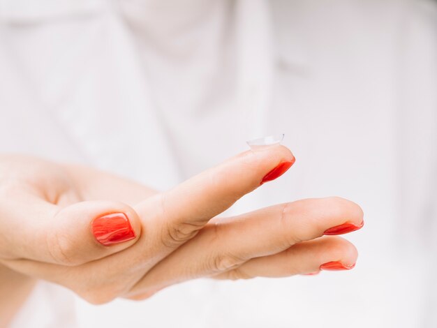 Mulher segurando lentes de contato no dedo