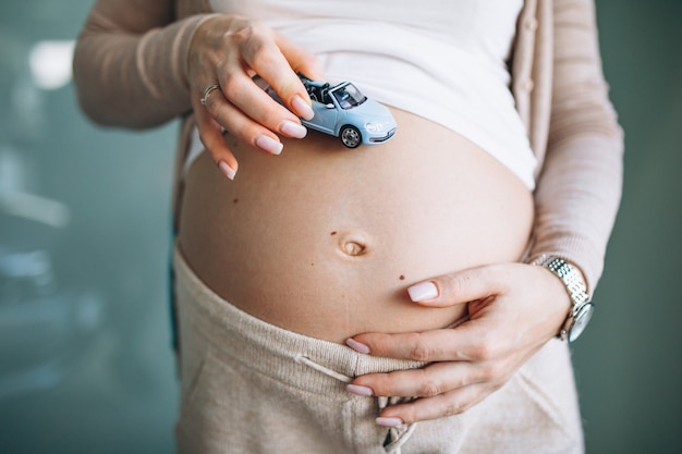 Mulher segurando modelo de carro pequeno pela barriga