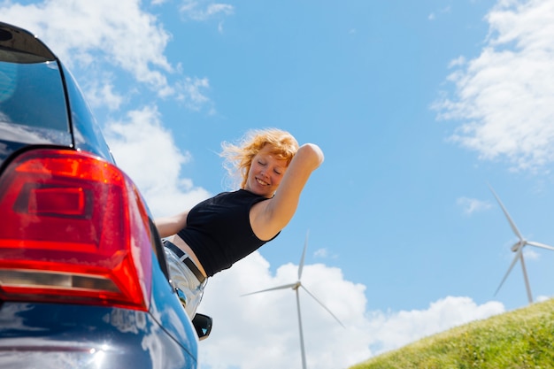 Mulher segurando o cabelo e olhando para baixo da janela do carro