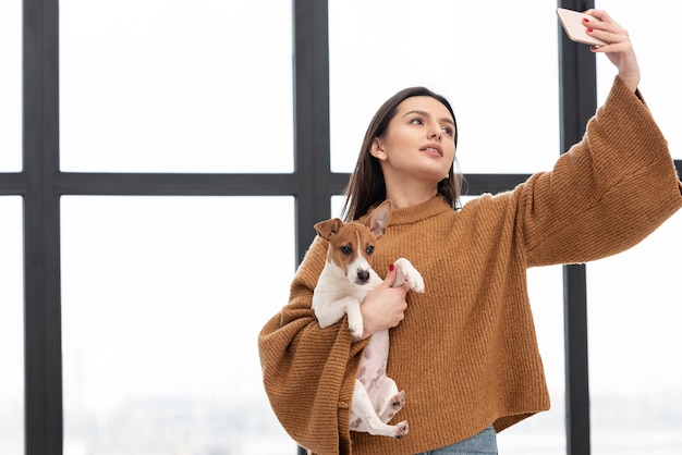 Mulher segurando o cachorro e tomar selfie