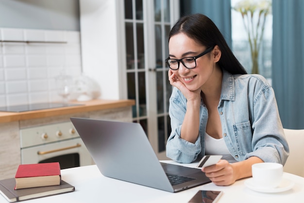 Mulher segurando o cartão de crédito e compras on-line no laptop