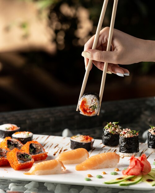 Mulher segurando o rolo de sushi com pauzinhos