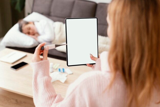 Mulher segurando o tablet e o termômetro