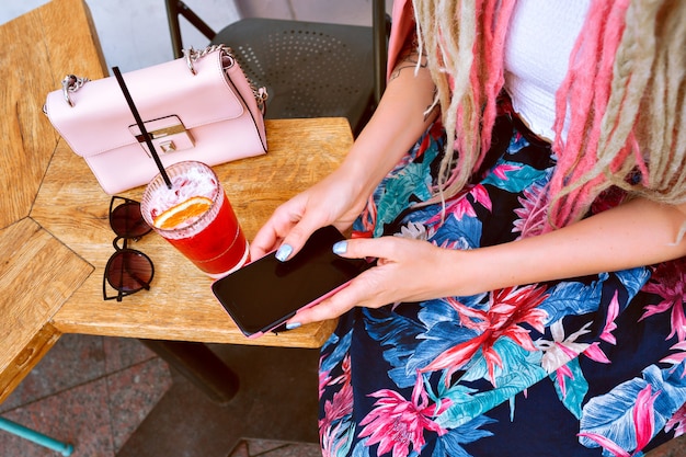 Mulher segurando seu smartphone e bebendo uma limonada saborosa