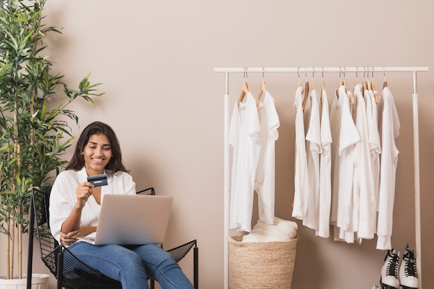 Mulher segurando um cartão e trabalhando no laptop