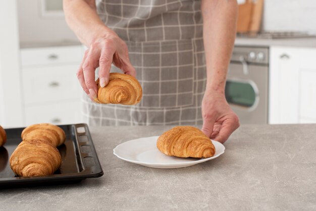 Mulher segurando um croissant na cozinha