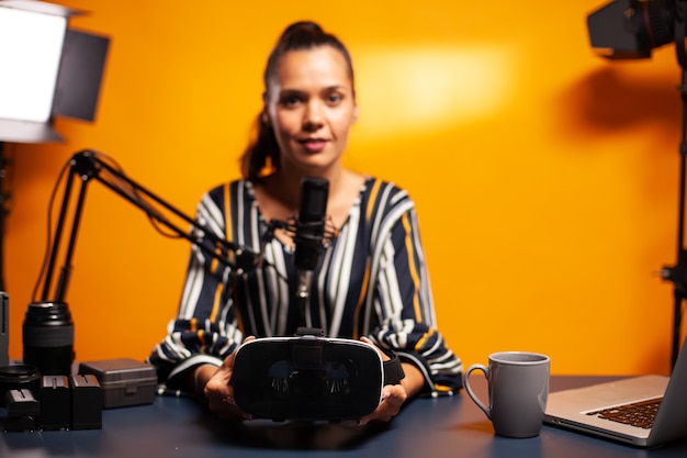 Foto grátis mulher segurando um fone de ouvido enquanto grava o videoblog no estúdio caseiro