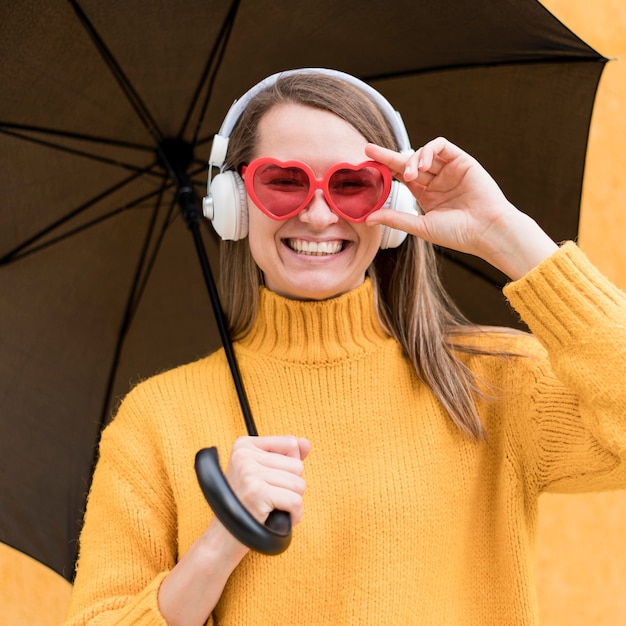 Foto grátis mulher segurando um guarda-chuva preto enquanto estiver usando fones de ouvido