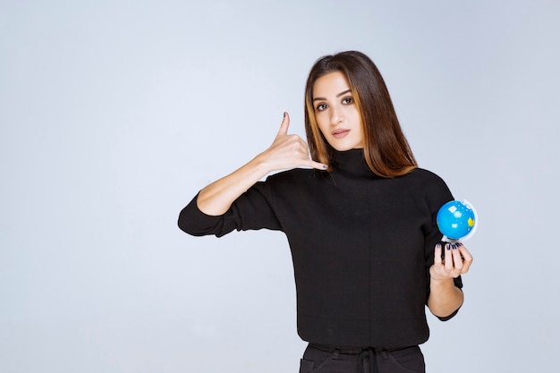 mulher segurando um mini globo e pedindo uma ligação.