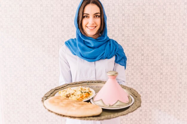 Mulher segurando um prato de comida árabe