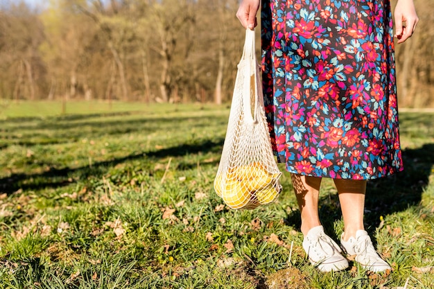 Mulher segurando um saco de frutas no parque