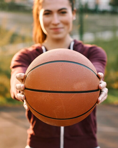 Mulher segurando uma bola de basquete na frente dela