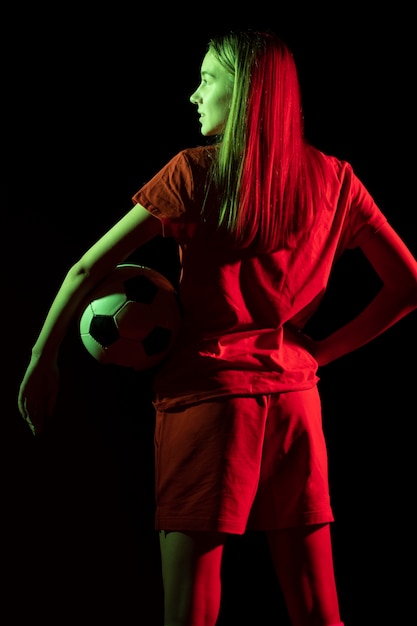 Mulher segurando uma bola de futebol de costas