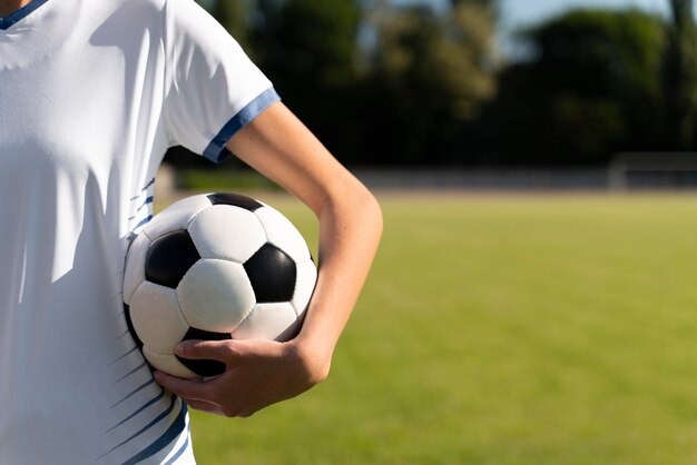 Mulher segurando uma bola de futebol no campo