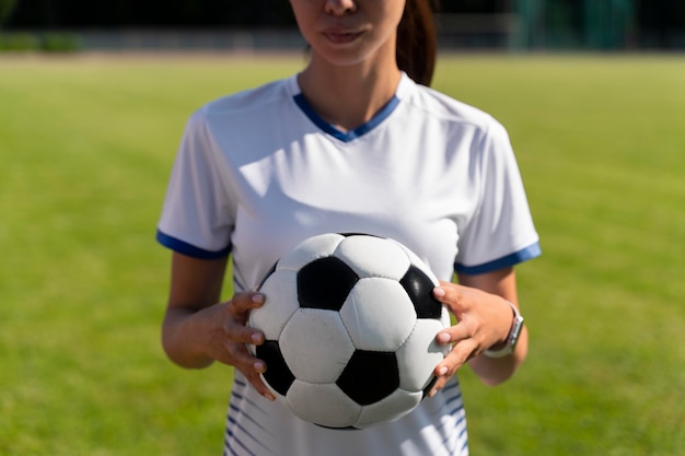 Mulher segurando uma bola de futebol no campo