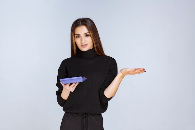 Mulher segurando uma calculadora azul e trabalhando nisso.