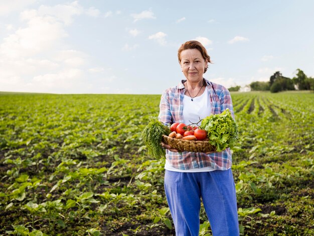 Mulher segurando uma cesta cheia de legumes com espaço de cópia