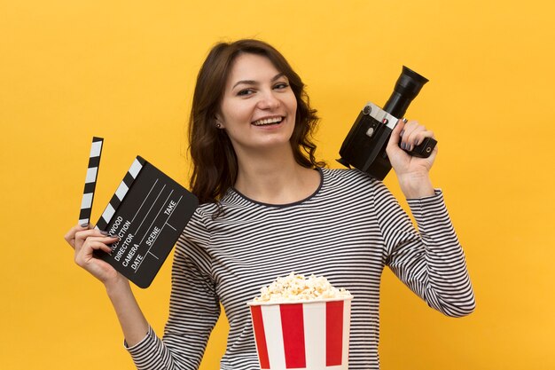 Mulher segurando uma claquete e uma câmera de filme