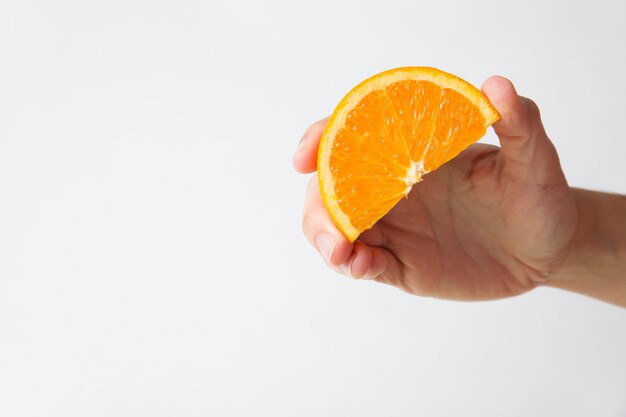 Mulher segurando uma fatia de laranja para suco