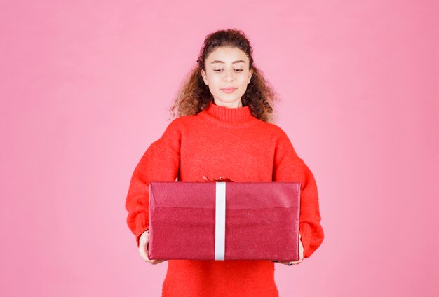 mulher segurando uma grande caixa vermelha de presente.