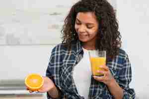 Foto grátis mulher segurando uma laranja e um copo de suco