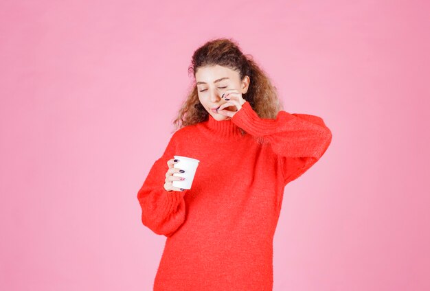 mulher segurando uma xícara de café descartável e apreciando o sabor.