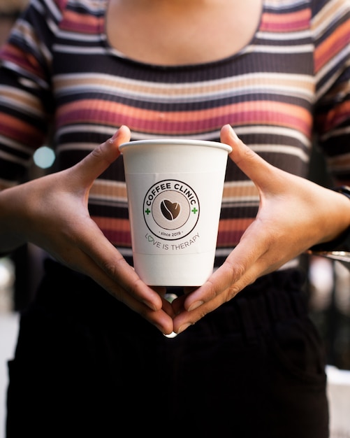 mulher segurando uma xícara de café descartável