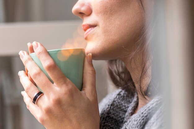 Mulher segurando uma xícara de café enquanto olha para fora