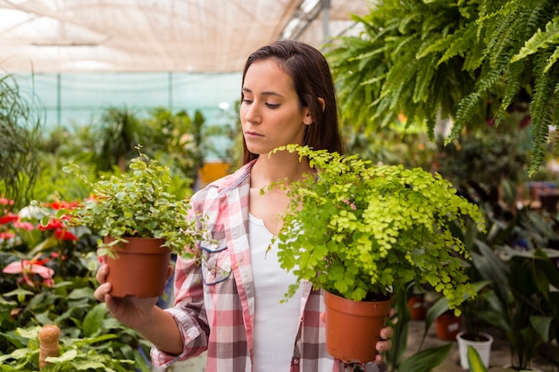 Mulher segurando vasos de flores em estufa