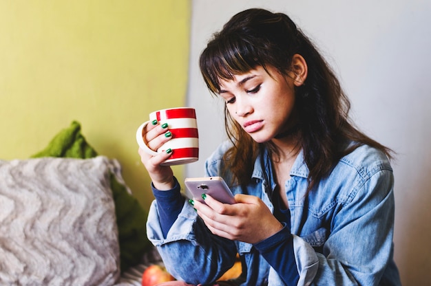 Mulher segurando xícara e usando o telefone